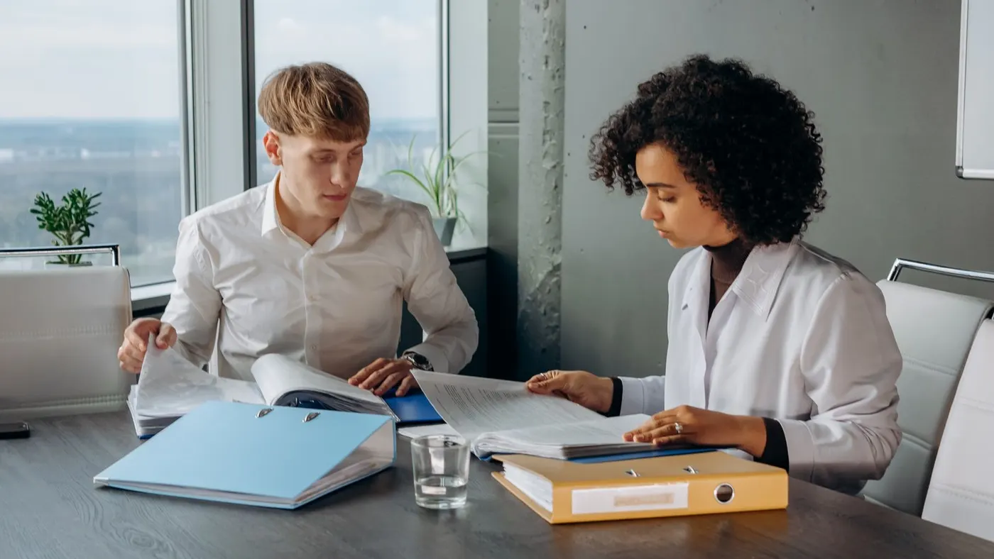 Two colleagues reading a financial report at a conference table